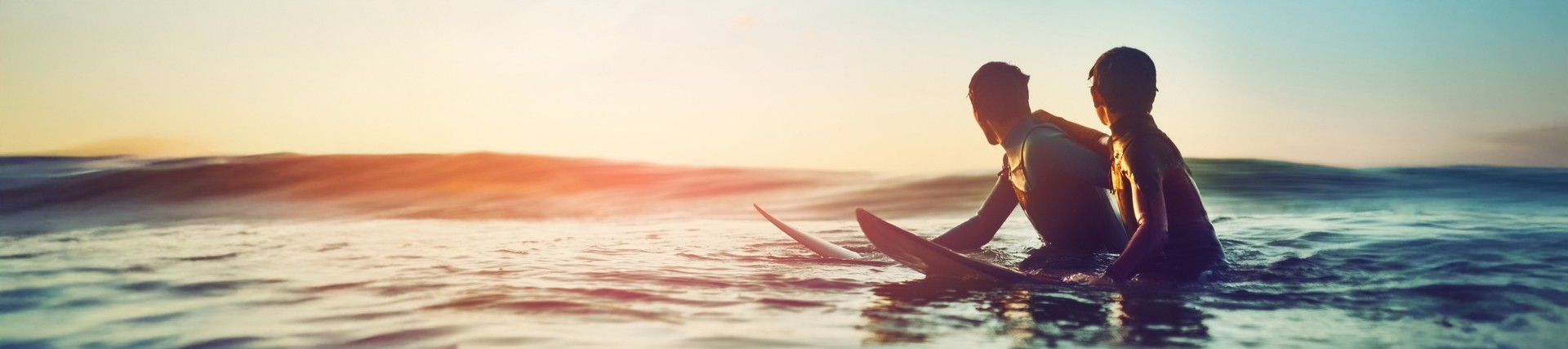 Two boys surfing, bathed in sunshine.